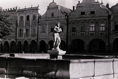 Neoclassical fountain featuring a muscular male statue in dynamic pose, set within a shallow rectangular basin. Symmetrical a...