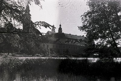 Vintage black-and-white shot of a grand Baroque-style building with twin towers and a central dome, partially obscured by ove...