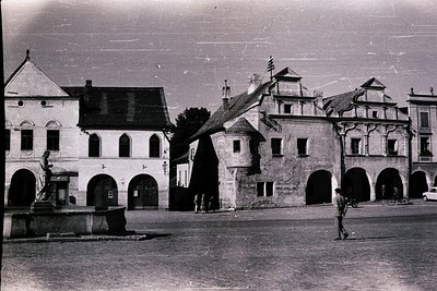 Black-and-white street scene featuring historic European architecture with arched ground floors and gabled upper levels, like...