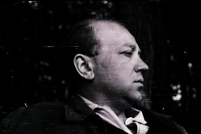 Portrait of a man in mid-profile, likely mid-20th century due to hairstyle and clothing. Dark suit with a white collar, sugge...