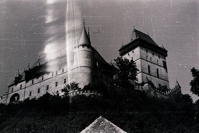 Historic castle with Gothic Revival architecture—turrets, crenellated walls, and steep gabled roofs. Likely Eastern European,...