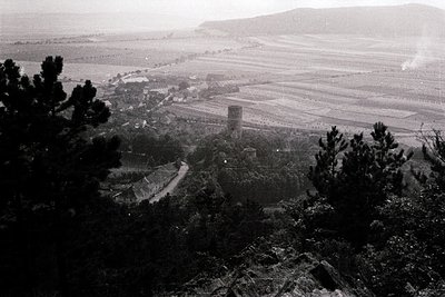 Vintage aerial view of a rural landscape featuring a prominent stone tower and agricultural fields. The scene suggests mid-20...