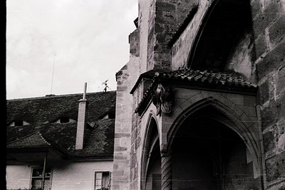 Gothic stone archway with sculpted gargoyle detail, likely part of a historic European church or cathedral. Weathered stonewo...