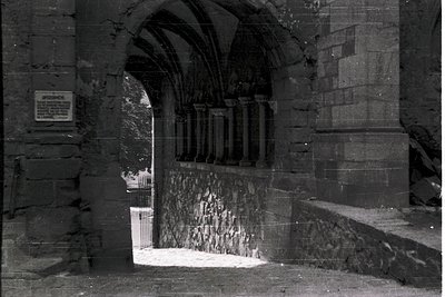 Gothic stone archway with pointed arches and buttressed walls, likely part of a historic European church or cathedral. The in...