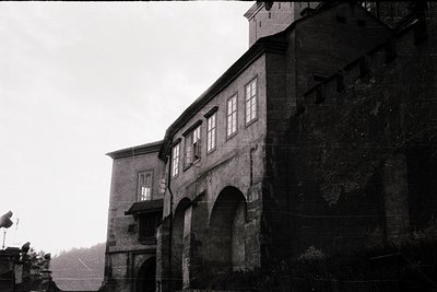 Monochrome shot of a fortified stone building with arched entryways and rectangular windows, likely a historic fortress or mo...
