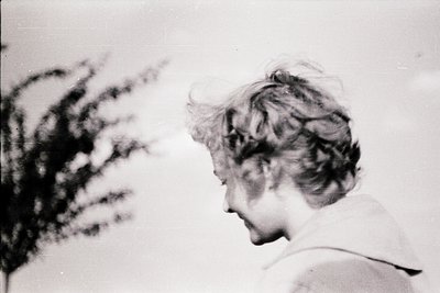 Vintage black-and-white portrait of a woman with short, voluminous hair, captured in profile. Soft focus and high-contrast li...
