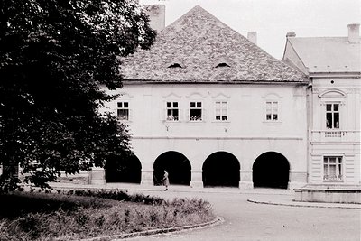 Neoclassical building with three arched ground-floor openings and symmetrical windows above, framed by a gabled roof. Archite...