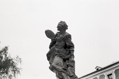 Neoclassical statue of a robed female figure holding a wreath, likely commemorative or symbolic. Detailed drapery and classic...