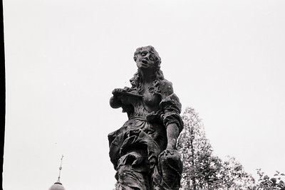 Bronze statue of a robed figure holding a scroll, likely a historical or religious figure. Detailed drapery and expressive fa...