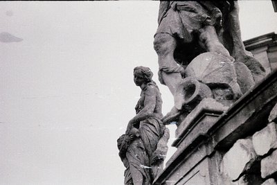 Detailed sculptural relief featuring a robed figure leaning on a draped, seated male figure atop ornate stonework. Likely Eur...