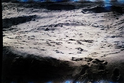 Vintage aerial view of a coastal dune system with sparse vegetation, likely captured in the mid-20th century. The undulating ...