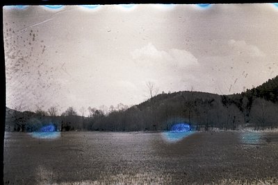 Vintage sepia-toned landscape with hand-tinted blue accents, likely a 35mm slide. Snow-covered field with leafless trees and ...