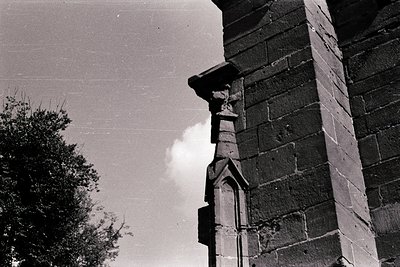 Gothic-style stone corbel with intricate carvings under a clear sky. Likely part of a historic European church or castle faça...