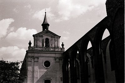 Neoclassical church bell tower with arched colonnade in mid-ground, black-and-white. Symmetrical facade features round window...
