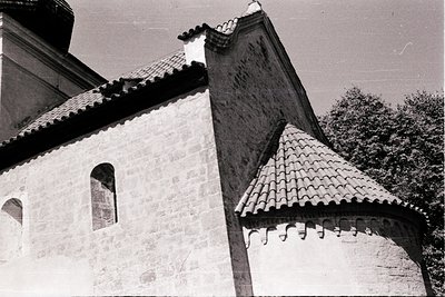 Historic stone building with tiled conical roof and arched windows, likely Eastern European architecture. The weathered textu...