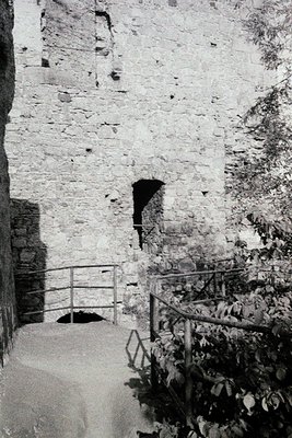 Historic stone staircase with wrought-iron railings leading upward through a weathered wall, likely part of a medieval fortre...