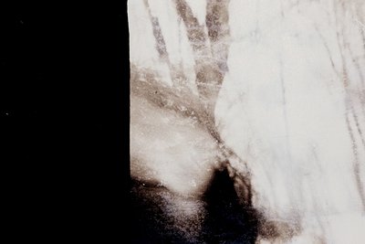 Vintage sepia-toned close-up of a person’s face, partially obscured by a dark, textured cloth or veil. Blurred details sugges...