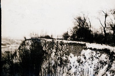 Vintage sepia-toned photograph of a coastal erosion scene with exposed rocky cliffs and remnants of vegetation. Snow patches ...