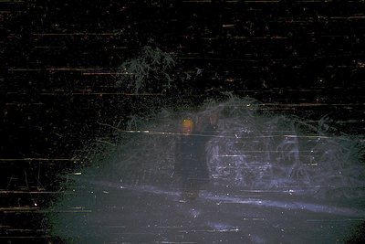 Long-exposure nighttime shot capturing light trails from passing vehicles on a wet road. Reflections create dynamic abstract ...