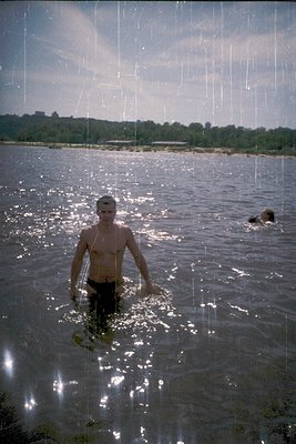 Mid-20th century outdoor scene featuring two men wading in shallow water under a grid of suspended ropes or cables, creating ...