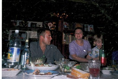 Family dining in a dimly lit, retro-style restaurant with neon signs and vintage decor. Mid-20th century ambiance, likely 197...