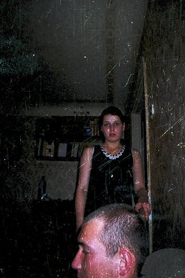 Vintage black-and-white photo of a woman in a sleeveless dress standing in a steam-filled bathroom, holding a towel. Reflecti...