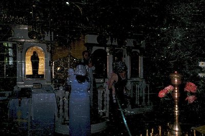 Orthodox church interior at night, featuring ornate iconostasis with golden mosaics and religious icons. Clergy in liturgical...