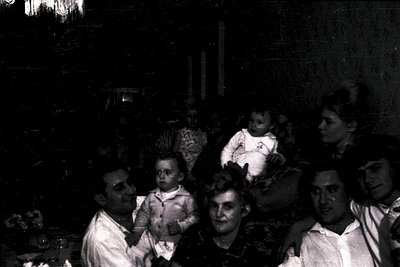 Vintage black-and-white group portrait, likely 1940s–1950s, featuring six adults and two children in formal attire. Men wear ...