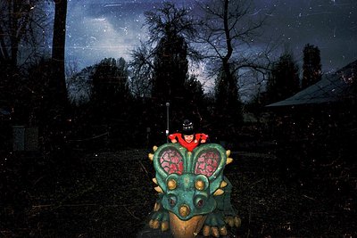 Vibrant dragon sculpture with glowing red eyes and gold accents, positioned in a dimly lit forest. Silhouetted figure in red ...
