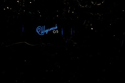 Minimalist neon sign reading "Ulysses 05" on black background with subtle starry texture. Modern typography with clean, geome...