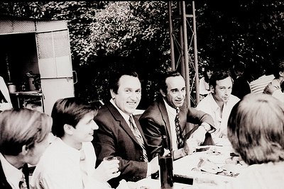 Mid-20th century (likely 1960s–70s) group photo of five men in formal attire at an outdoor gathering. Central figure in a dar...