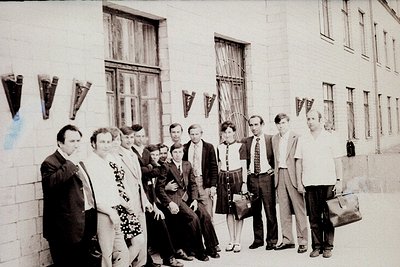 Group photo outside a Soviet-era institutional building, likely from the 1970s–1980s. Ten individuals pose in formal attire: ...