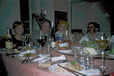Vintage group portrait at a festive dinner table, featuring four women in 1970s-style headbands and dark attire. Reflections ...