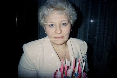 Vintage portrait of an individual in a light-colored blazer, holding a bouquet of pink and white flowers. Polaroid-style grai...