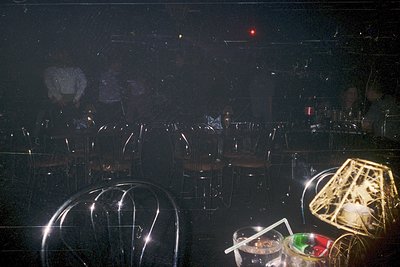 Low-angle shot of a dimly lit nightclub interior with geometric lighting fixtures. Circular and angular spotlights cast sharp...