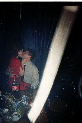 Intimate moment captured through a frosted window, revealing a couple embracing in a dimly lit room. The man in a light-color...