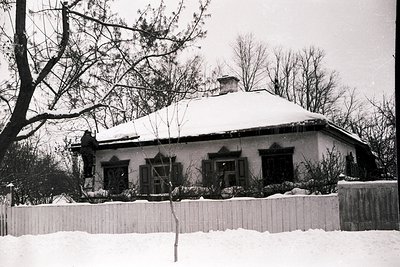 Single-story Soviet-era residential building with gable roof, snow-covered exterior, and whitewashed walls. Decorative triang...