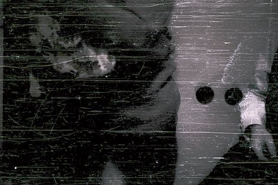 Vintage black-and-white photo of a woman’s face pressed against a frosted glass window, showing faint reflections of trees an...