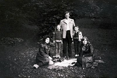 Family portrait in rugged alpine terrain, 1960s–1970s. Five individuals pose outdoors—two adults standing, three children (tw...