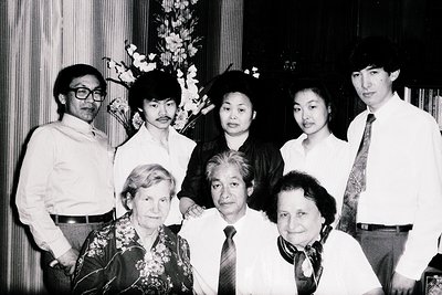 Group portrait from the 1970s–1980s, likely East/Southeast Asia. Seven individuals pose indoors, formal attire (ties, blazers...