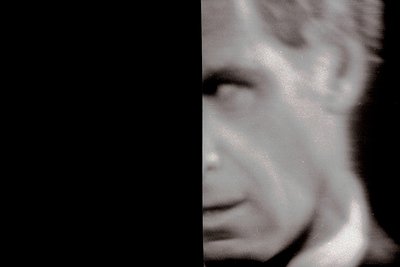 Blurred black-and-white portrait of a man in profile, likely mid-20th century. Soft focus reveals clean-shaven face with high...