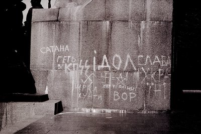 Graffiti on weathered stone wall with Cyrillic and Latin script. Mixed messages include "САТАНА" (Satan), "КОССИДАЛА" (Kossid...