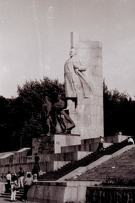 Monumental Soviet-era statue depicting a central figure in a robe holding a raised arm, flanked by smaller figures in militar...