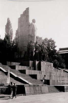 Monumental Soviet-era statue complex featuring a towering seated figure atop a tiered concrete platform, flanked by smaller s...
