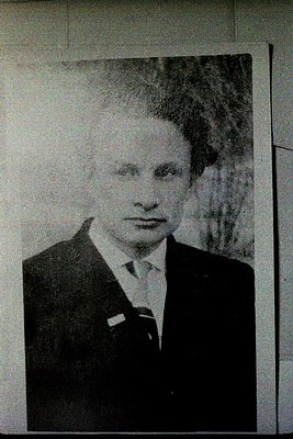 Black-and-white portrait of a man in formal attire: dark suit, white shirt, and bow tie. Background suggests an indoor settin...