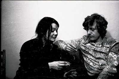 Black-and-white candid of two individuals in intimate, candid embrace—man in patterned shirt, woman in dark coat. Spontaneous...