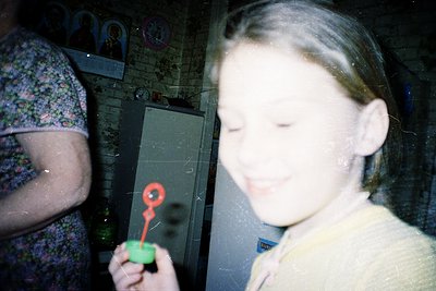 Vintage indoor portrait of two children playing with a toy keychain (red key + green base). Child in foreground wears a light...
