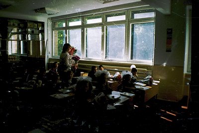 Vintage classroom with natural light streaming through large, divided windows. Teacher in traditional attire stands at front,...