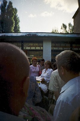 Blurred mid-20th-century street scene through a bus window, showing four women in 1960s-70s attire—one in floral dress, other...