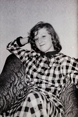 Portrait of a woman in a 1950s-60s plaid blouse, resting chin on hand. Soft focus and monochrome style suggests vintage famil...